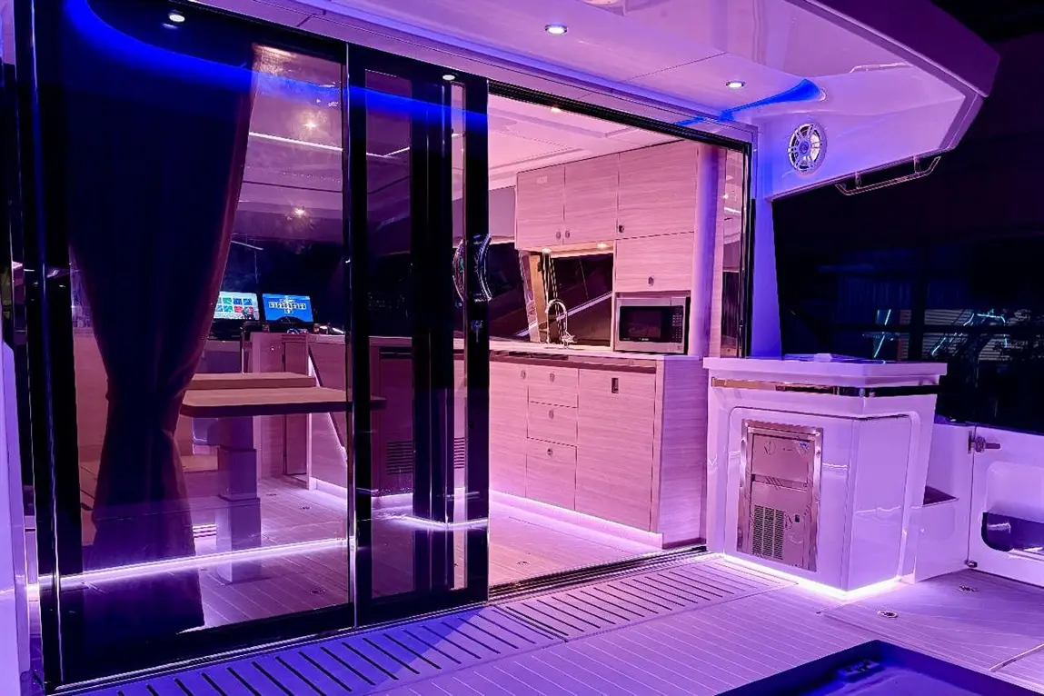 Luxurious yacht interior featuring a modern kitchen, dining table, and ambient purple lighting, creating a stylish atmosphere.